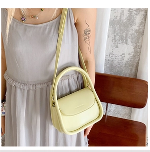 Close-up of light green crossbody bag with semi-circle handle on model for summer style