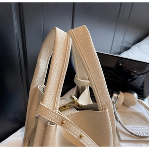 Close-up of beige lychee grain leather bucket bag with gold hardware and accessories