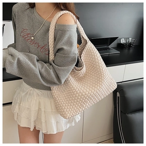 Detailed close-up of cream woven hobo tote bag texture with thick braided shoulder strap