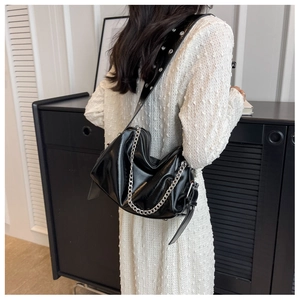 Détail du sac hobo noir brillant avec chaîne argentée et bandoulière à œillets