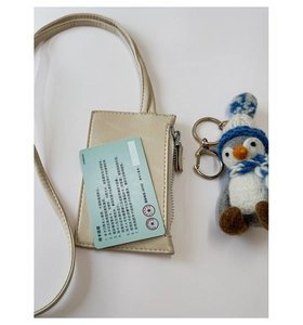 Close-up of beige leather card holder with neck strap and silver zipper detail