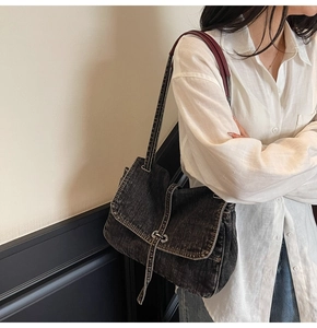 Detail of vintage denim tote bag showing metal buckle and contrast burgundy shoulder strap