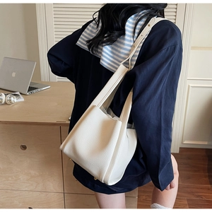 Close-up of white lychee textured leather bucket bag featuring soft tote design