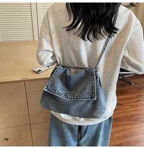 Model wearing a retro blue denim crossbody bag with silver chain strap and distressed finish