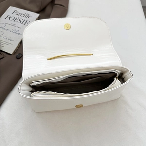 Sac bandoulière blanc avec épingle de sûreté montrant les compartiments et le fermoir doré