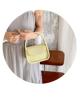 Detail of light green mini handbag with smooth faux leather finish and top handle