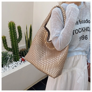 Detail of champagne gold woven tote bag with wide cross-weave texture on model shoulder
