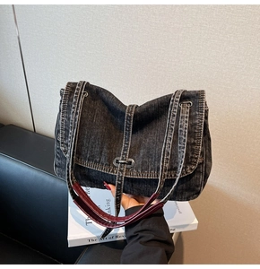 Detail of gray washed denim shoulder bag with retro metal buckle and leather strap accent