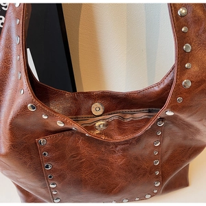 Détail de rivets argentés et fermoir magnétique d'un sac hobo vintage marron avec doublure