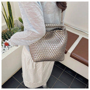 Detail of silver metallic woven bucket bag with thick textures and long shoulder strap