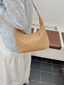 Women's light brown woven shoulder bag with silver hardware and chic minimalist style