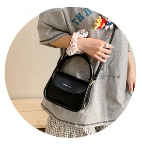 Detail of a black leather crossbody bag with top handle and Fashion & Bags lettering