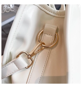 Detailed close-up of premium gold hardware and neat stitching on cream white handbag strap