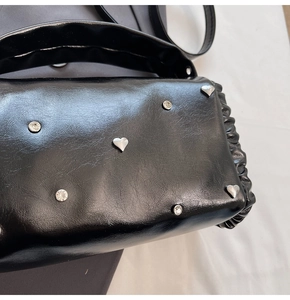 Detail of black glossy leather bag with silver heart studs and sparkling rhinestones