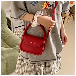 Detailed view of a chic red leather crossbody bag with top handle and fashion logo