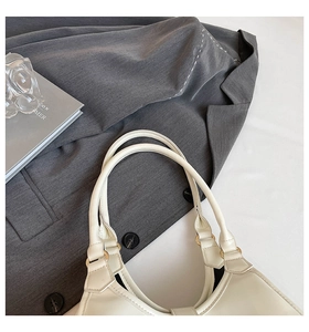 Detail of cream leather handbag with gold metal rings and elegant top handles