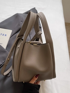 Taupe pebbled leather bucket bag with top handles and adjustable shoulder strap