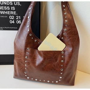 Détail macro du sac hobo en cuir huilé marron foncé avec rivets métalliques argentés