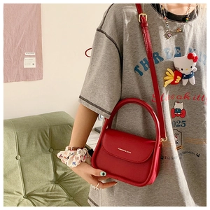 Red leather handbag with adjustable strap and 'FASHION & BAGS' text print on the front