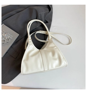 Detail view of cream white tote bag featuring matte leather texture and gold hardware