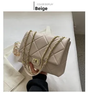 Détail d'un sac beige matelassé avec fermoir doré et bandoulière en chaîne dans un décor chic