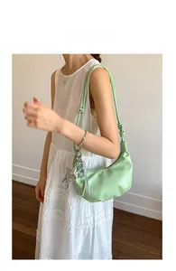 Detail of light green crescent underarm bag with silver star pendant and long strap
