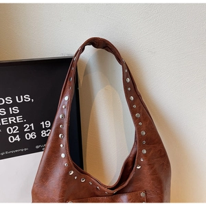 Détails de ce sac hobo en cuir vieilli marron avec des rivets métalliques sur la bandoulière