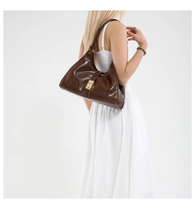 Detailed view of a vintage brown leather shoulder bag with a gold metal lock on a model