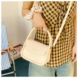 Detail of creamy white mini crossbody bag with top handle and adjustable strap