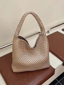 Champagne gold woven hobo bag with intrecciato design on a leather bench