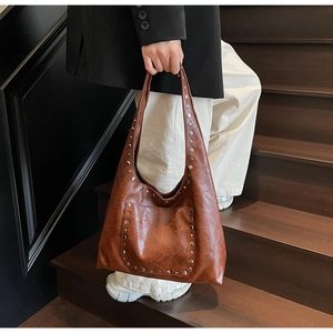 Détails du sac cabas marron vintage avec clous argentés et texture cuir huilé