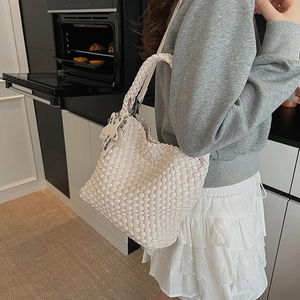 Detail of white hand-woven leather tote bag with wide strap and star charm on shoulder