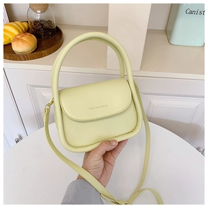 Detail of light yellow crossbody bag featuring round handle and FASHION & BAGS logo