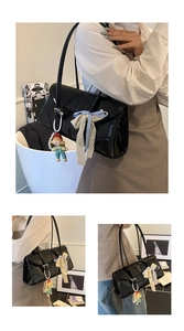 Detail of black faux leather tote bag with lace bow and cute doll charm accent
