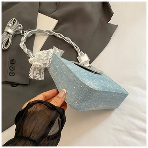 Détail du sac baguette en jean bleu clair avec strass, bandoulière argentée et dentelle