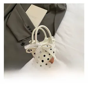 Close-up of white polka dot handbag featuring lace bow and elegant pearl details