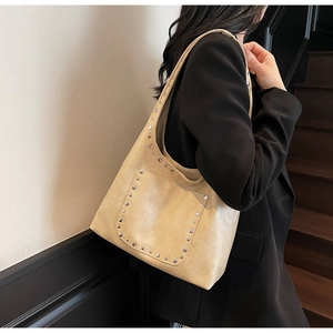 Détails des rivets et de la texture en cuir PU sur un sac à bandoulière beige de style biker
