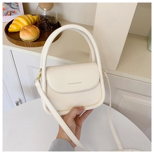 Detail shot of a cream PU leather handbag with gold FASHION & BAGS lettering and hardware