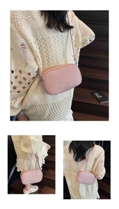 Detail of pink lychee texture leather crossbody bag with silver logo and adjustable strap