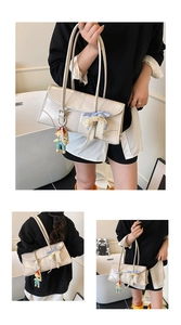 Detail of beige rectangular shoulder bag with blue plaid bow and cute doll pendant