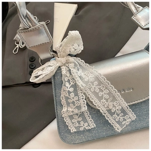 Détail du sac baguette en denim vintage avec strass et un nœud décoratif en dentelle