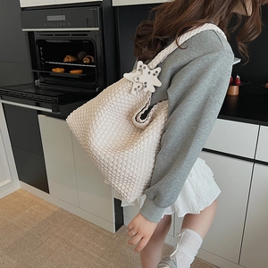 Detail of hand-woven cream tote bag with star charm and thick braided shoulder strap