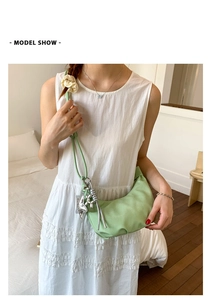 Detail of light green crescent shoulder bag with silver charms and scrunchie accessory