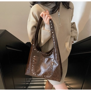 Détail du sac cabas vintage en cuir ciré avec rivets argentés sur la bandoulière