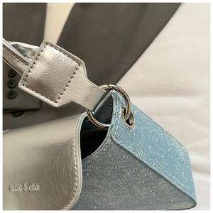 Détail de la texture denim bleu clair avec accents argentés et boucle de marque