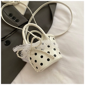 Detailed macro shot of mini polka dot bucket bag with lace bow and pearl charms