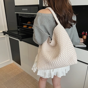 Detail of hand-woven beige tote bag with intricate texture in a modern lifestyle setting