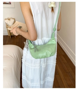 Detail of light green hobo bag with pleated texture and silver star pendant accessory