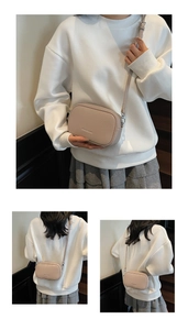 Detailed view of the textured lychee leather and fashion lettering on the beige crossbody bag