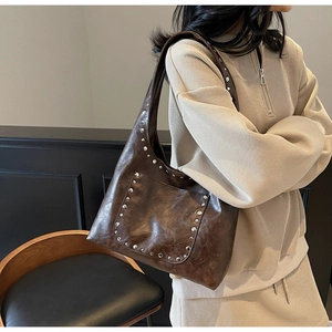 Détail latéral du sac cabas marron foncé avec rivets et finition cuir vieilli sur l'épaule